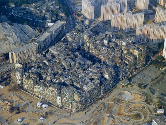 Aerial photo of the Walled City as a single dense block of buildings surrounded by roads and newer towers, 1989.