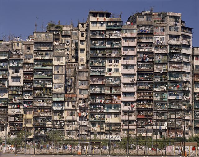 A long facade of densely packed apartment blocks with a playground in front, 1993.